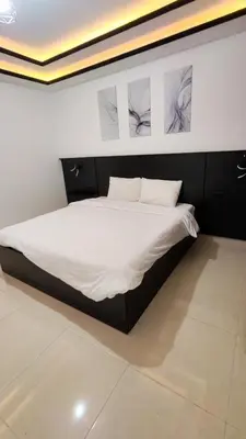 a bed in a room with two pictures on the wall at La Perla Apertment Family in Amman
