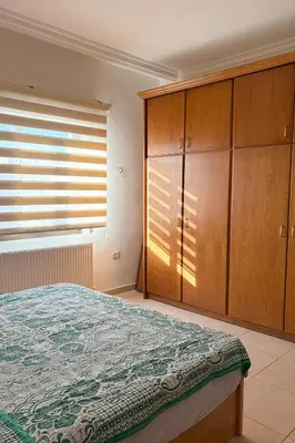 a bedroom with a bed and wooden cabinets at Comfy Apt at Jandawil -only Families- in Amman