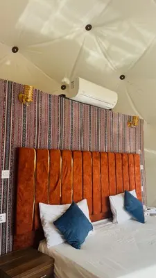 a bed with two blue pillows on top of it at wadi rum Bubble lunara luxury camp in Wadi Rum