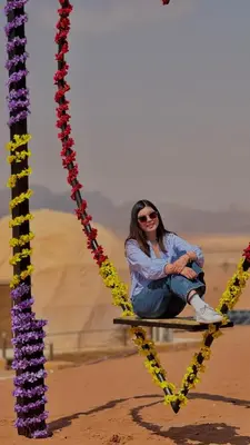 a woman sitting on a swing in the desert at wadi rum Bubble lunara luxury camp in Wadi Rum