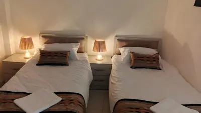 two beds in a small room with two lamps at hotel amman in Amman