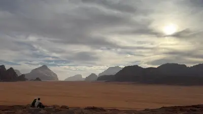 two people sitting on the rocks in the desert at HALA RUM Luxury camp & Bubbles Hotel in Disah