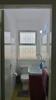 a bathroom with a toilet and a sink and a window at Panoramic GUESTHOUSE - OUM ALI in Aş Şāfī