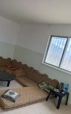 a large couch in a room with a window at Panoramic GUESTHOUSE - OUM ALI in Aş Şāfī
