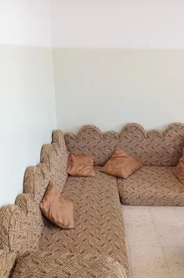 a brown couch with pillows sitting in a room at Panoramic GUESTHOUSE - OUM ALI in Aş Şāfī