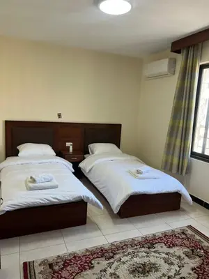a bedroom with two beds and a rug at Badan Suites & Hotel in Amman