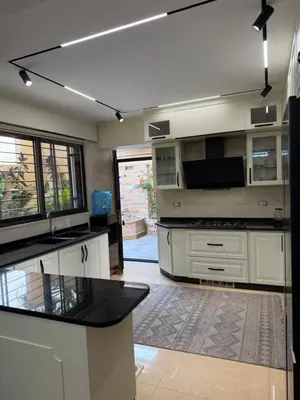 a kitchen with white cabinets and a black counter top at مطر in Amman