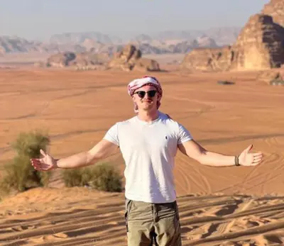 a man standing in the desert with his arms outstretched at Rum luxury camp hotel in Wadi Rum