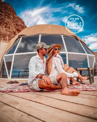 a man and a woman sitting in front of a boat at WADi RUM BUBBLE in Wadi Rum