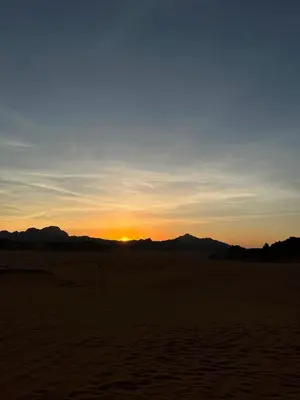 a sunset in the desert with mountains in the background at Nile bedouin camp in Aqaba