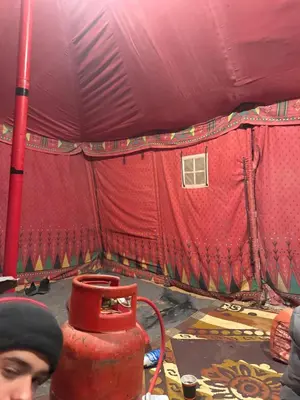 a man standing in front of a red tent at RUM LOREN lUXURY CAMP in Wadi Rum