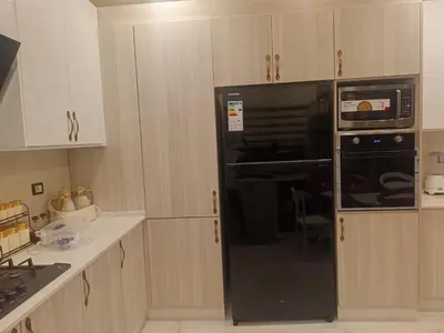 a black microwave in a kitchen with wooden cabinets at شقق في عمان in Al Jafr