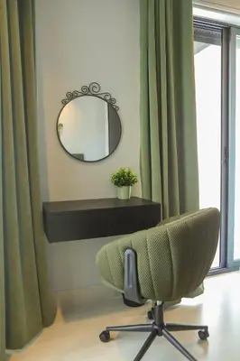 a mirror and a chair in a room with curtains at The FWD Living - FWD2 in Amman