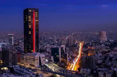 a city skyline at night with a tall building at Skyline Residence Apartment Stunning City Views in Amman