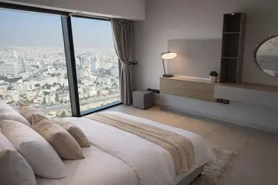 a bedroom with a large bed with a large window at Skyline Residence Apartment Stunning City Views in Amman