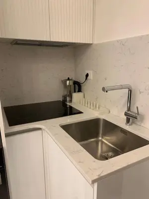 a kitchen with a stainless steel sink and white cabinets at Boulevard Comfort Haven, apt with stunning veiw in Amman