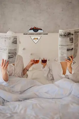 two people laying in bed reading newspapers and drinking wine at RUM LOREN lUXURY CAMP in Wadi Rum