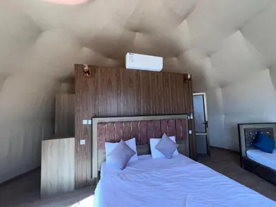 a bedroom with a large bed with a wooden headboard at Wadi Rum Desert Wonders Camp in Disah
