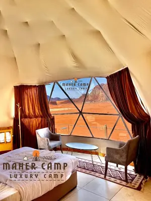 a bedroom with a bed and a large window at Wadi rum maher luxury camp in Wadi Rum