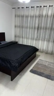 a bedroom with a bed and a curtain and a rug at Deir Ghbar apartment 116 in Amman