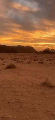 an empty desert with a sunset in the background at Golden Camp in Wadi Rum