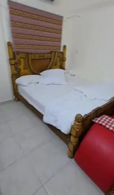 a bed with a wooden headboard and a red pillow at عبدالرحمن الشطناوي in Aqaba