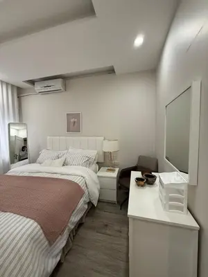 a bedroom with two beds and a desk with a mirror at Modern Apartment, Untouched & Ready to Stay in Amman