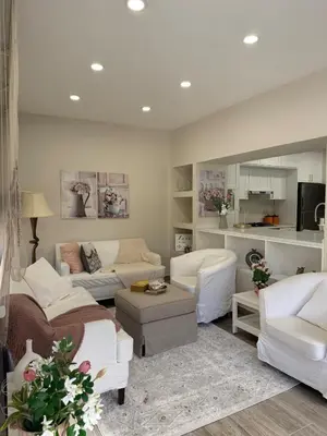 a living room with white furniture and a kitchen at Modern Apartment, Untouched & Ready to Stay in Amman