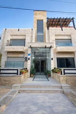 a large brick building with a door and stairs at Abdoun Grand Family Apartment in Amman