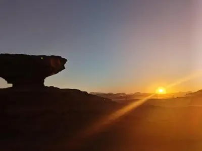 a sunset in the desert with the sun setting at DESERT PULSE lUXURY CAMP in Wadi Rum