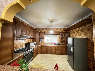 a kitchen with wooden cabinets and a black refrigerator at Jad Apartment in irbid in Irbid