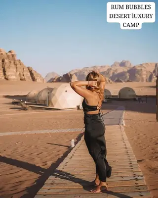 a woman standing on the beach looking at the desert at RUM BUBBLES DESERT lUXURY CAMP in Wadi Rum