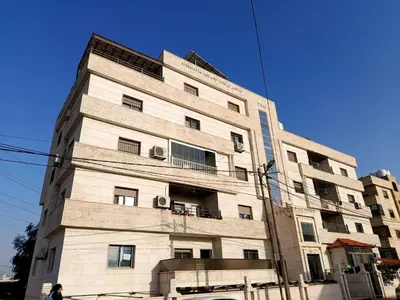 a tall white building with windows on a street at شقه مفروشه للايجار بجانب الكارفور اربد in Irbid