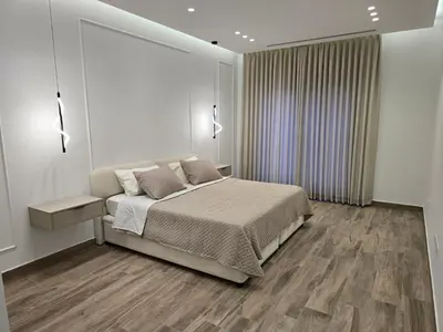 a white bedroom with a bed and a mirror at Two-bedroom family friendly modern apartment in Amman