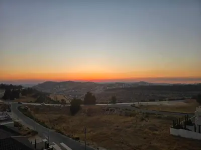 a sunset from the top of a hill with a road at Two-bedroom family friendly modern apartment in Amman