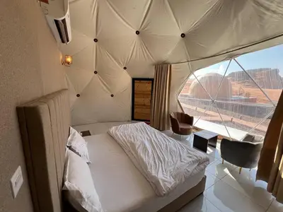 a bedroom with a bed and a large window at Golden Dunes Camp Wadi Rum in Wadi Rum