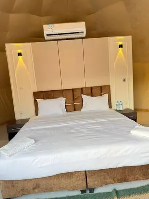 a large white bed with two pillows and a fan at Golden Dunes Camp Wadi Rum in Wadi Rum