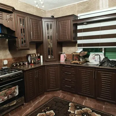 a kitchen with wooden cabinets and a kitchen rug at المناره هاوس in Wadi Musa