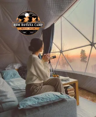 a woman sitting on a bed in a tent at WADi RUM ROTANA BUBBLE lUXURY CAMP in Wadi Rum
