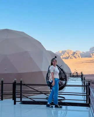 a woman standing in front of a tent in the desert at WADi RUM ROTANA BUBBLE lUXURY CAMP in Wadi Rum