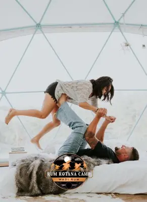 a man and a woman are jumping on a bed at WADi RUM ROTANA BUBBLE lUXURY CAMP in Wadi Rum