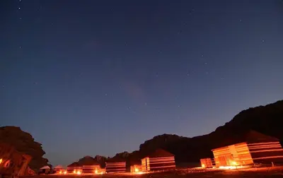 a group of lodges at night with the stars at Bedouin Whispers Camp wadirum in Wadi Rum