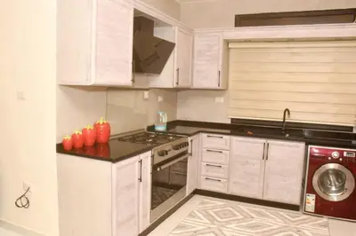 a kitchen with white cabinets and a stove top oven at شقة مفروشة مع ساحة خارجية قرب دوار اليوسفي in Irbid