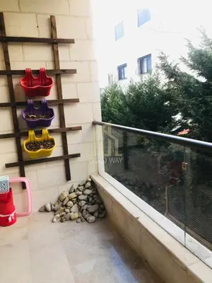 a balcony with red and yellow chairs on a wall at Chic 2-Bedroom - Fully Furnished in Amman