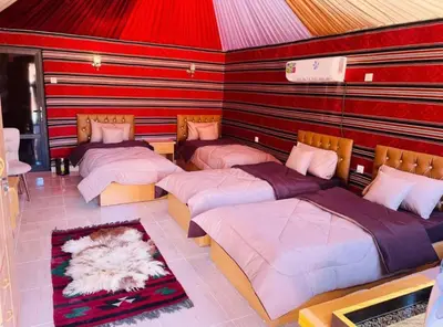 a group of four beds in a room at Wadi Rum Nomad Way Camp in Wadi Rum