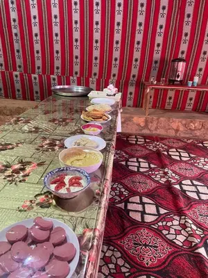 a table with plates of food on top at Wadi Rum Nomad Way Camp in Wadi Rum