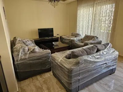 a living room with two couches covered in plastic at MK7 - Two Bedroom Apartment in Amman
