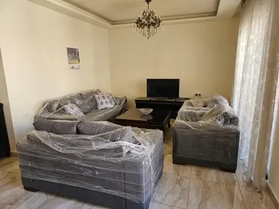 a living room with two beds covered in plastic at MK7 - Two Bedroom Apartment in Amman