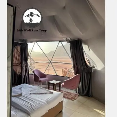 a room with a bed and chairs and a window at Mila Wadi Rum Camp in Wadi Rum