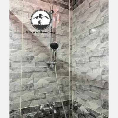 a bathroom with a shower with a stone wall at Mila Wadi Rum Camp in Wadi Rum